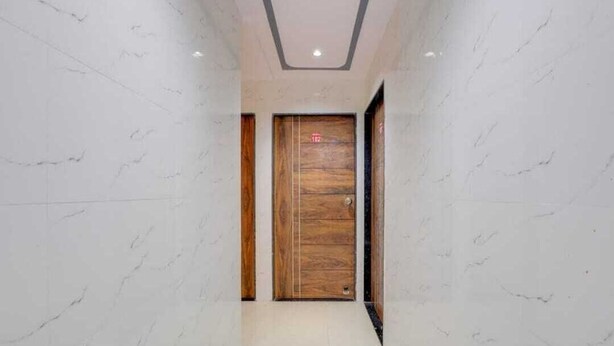 Un corridoio con pareti in marmo e una porta in legno con una targa identificativa.