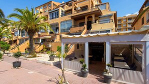 A multi-story hotel with balconies, a covered outdoor seating area, and potted plants. - Perseo - Apartment In Torrevieja. Free Wifi (, Alicante)