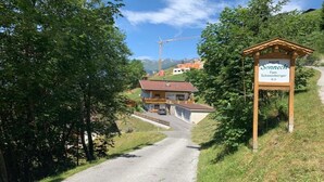 A rural road leading to a building with a sign reading "Haus Sonneck Fam. Schwienberger 16 B". - Apartment in Zillertal near Ski Slopes (Zell am Ziller)