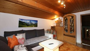 A cozy living room with a wooden ceiling, a sofa with cushions, a coffee table, and a cabinet with glass doors. - Apartment in Zillertal near Ski Slopes (Zell am Ziller)