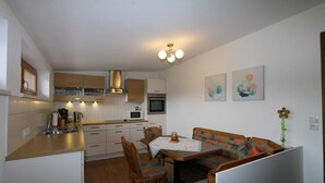 A compact kitchen with a dining area, wooden cabinets, a microwave, and a small table with chairs. - Apartment in Zillertal near Ski Slopes (Zell am Ziller)