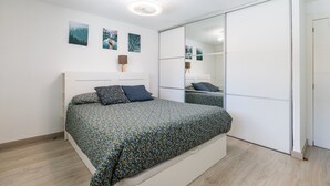 A bedroom with a bed, a wardrobe, and a mirror.