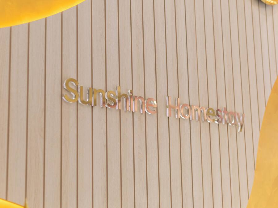 Un letrero con la inscripción 'Sunshine Homestay' sobre un fondo de madera.