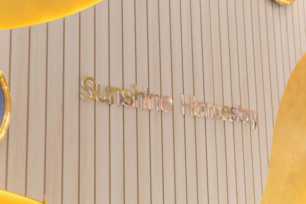 A sign with the words "Sunshine Homestay" on a wooden background.