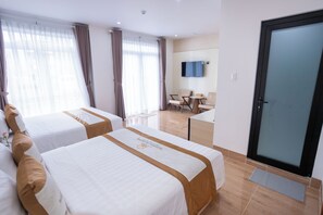 A hotel room with two beds, a desk, a chair, and a television on the wall. - Sunshine Homestay (Bac Lieu)