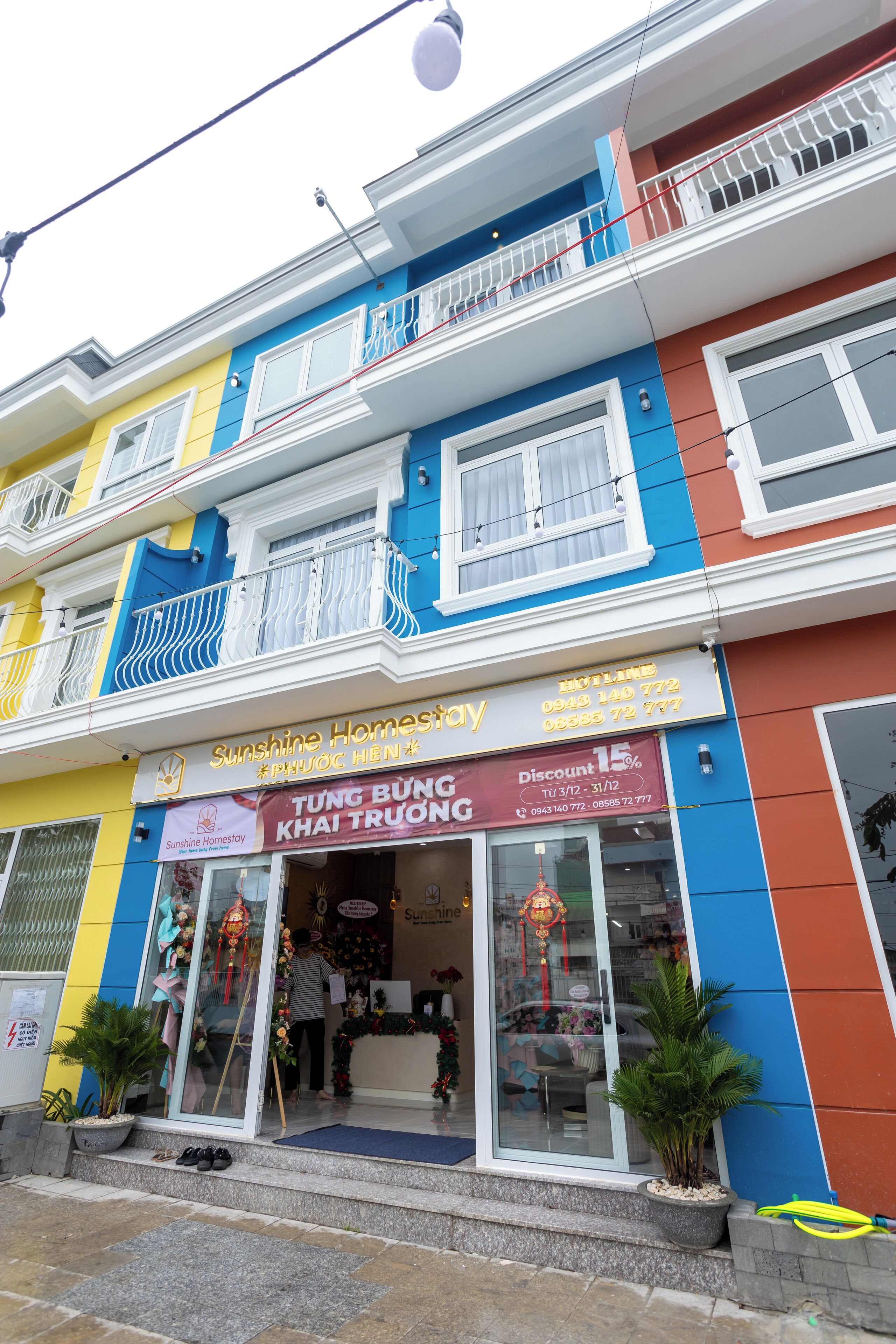A colorful building with a storefront named 'Sunshine Homestay' offering a 15% discount.