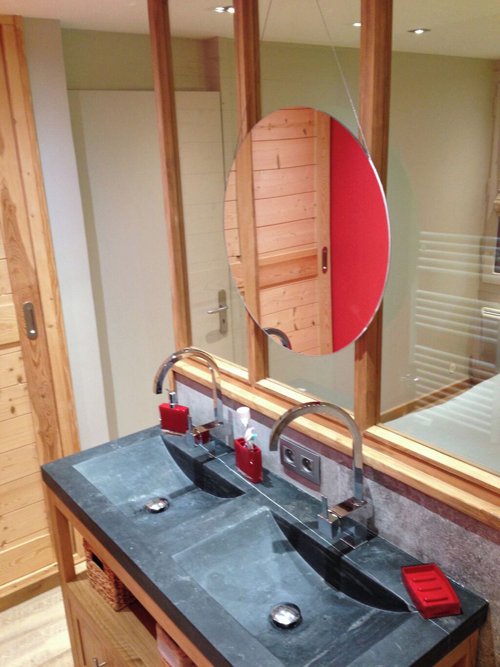Une salle de bain avec deux lavabos, un grand miroir et un lambris en bois.