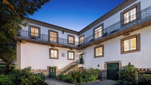 A courtyard with a white building, a green door, and a staircase leading to a balcony. - Solar das Tilias - Historic House (Seia)
