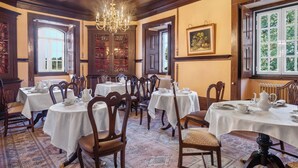 A dining area with round tables, chairs, and a chandelier. - Solar das Tilias - Historic House (Seia)