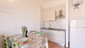 A compact kitchen with white tiles, a built-in stove, and a white refrigerator.