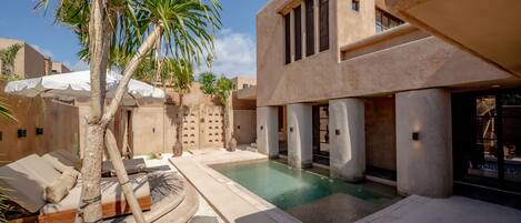 A pool area with lounge chairs and a palm tree.