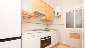 A compact kitchen with white cabinets, a built-in oven, and a microwave. - Velbar - Apartment In Cádiz. Free Wifi (, Cádiz)