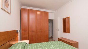 A bedroom with a bed, a wooden wardrobe, a bedside table, and a mirror on the wall. - Velbar - Apartment In Cádiz. Free Wifi (, Cádiz)