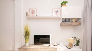 A modern living room with a flat-screen TV, a coffee table, and decorative items. - Velbar - Apartment In Cádiz. Free Wifi (, Cádiz)