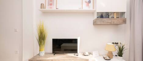 A modern living room with a flat-screen TV, a coffee table, and decorative items.