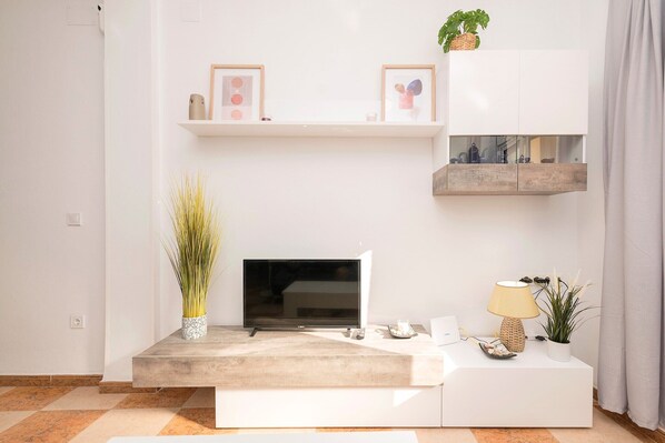 A modern living room with a flat-screen TV, a coffee table, and decorative items.
