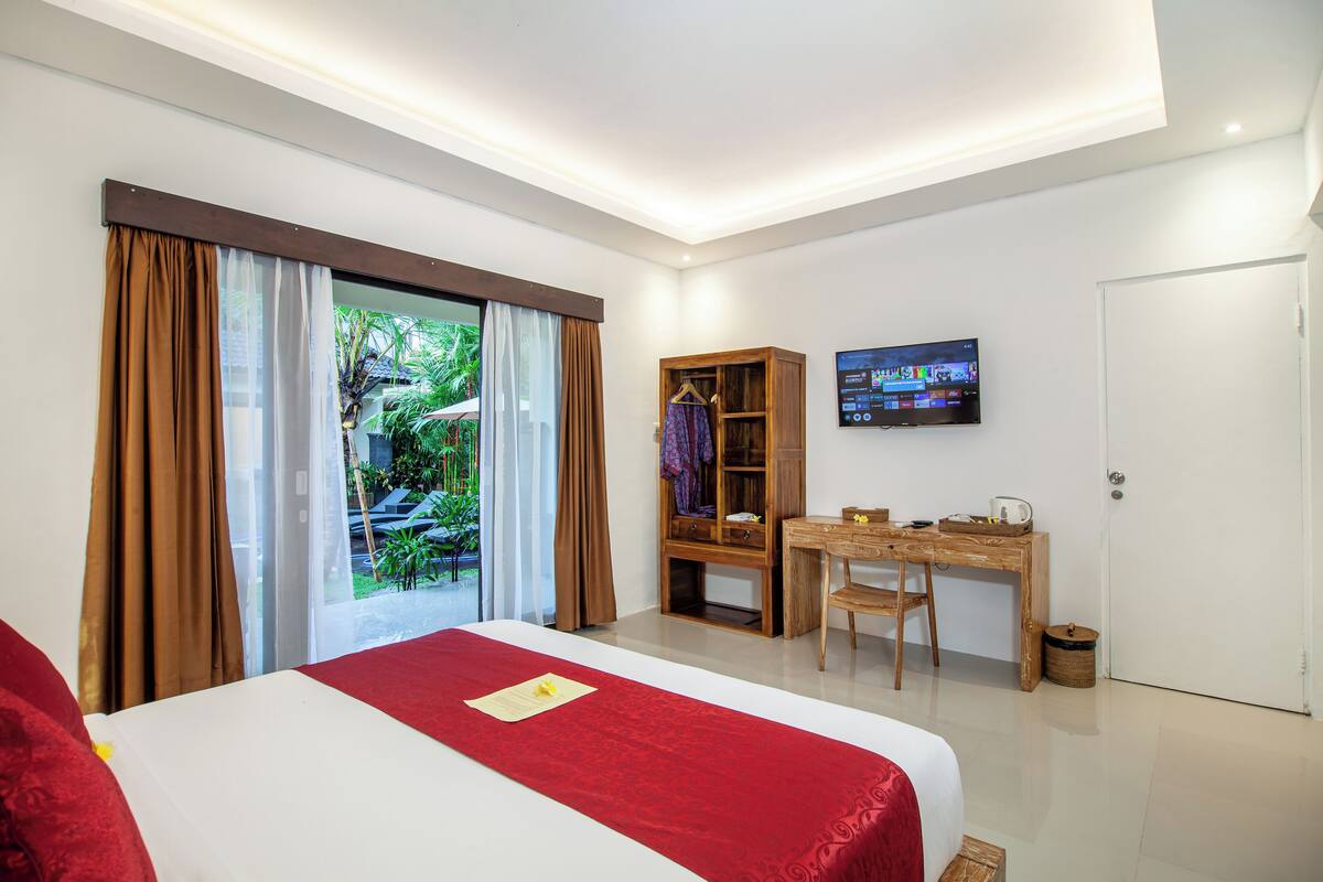 A hotel room with a bed, a desk, a TV, and a wardrobe.