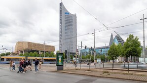 A busy urban street with pedestrians, a tram, and modern buildings. - FeelgooD Apartment COZY Leipzig City-Center with underground parking space (Leipzig)