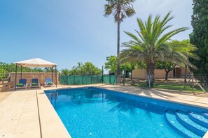 Ein Pool mit Liegestühlen und einer überdachten Sitzgelegenheit.