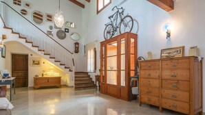 Un vaste espace de vie agrémenté d’un escalier en bois, d’une grande armoire aux portes vitrées et d’un vélo fixé au mur.