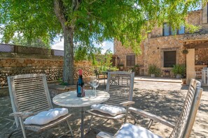 An outdoor patio with stone walls, wooden furniture, and potted plants.