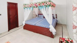 Un dormitorio con una cama con dosel, un ventilador de techo y una puerta de madera.