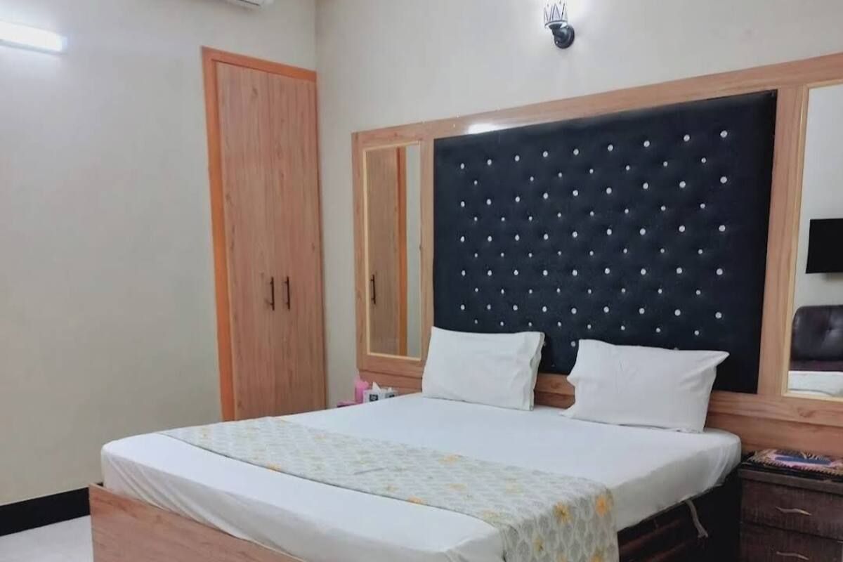 A bedroom with a bed, wooden wardrobe, and a ceiling fan.