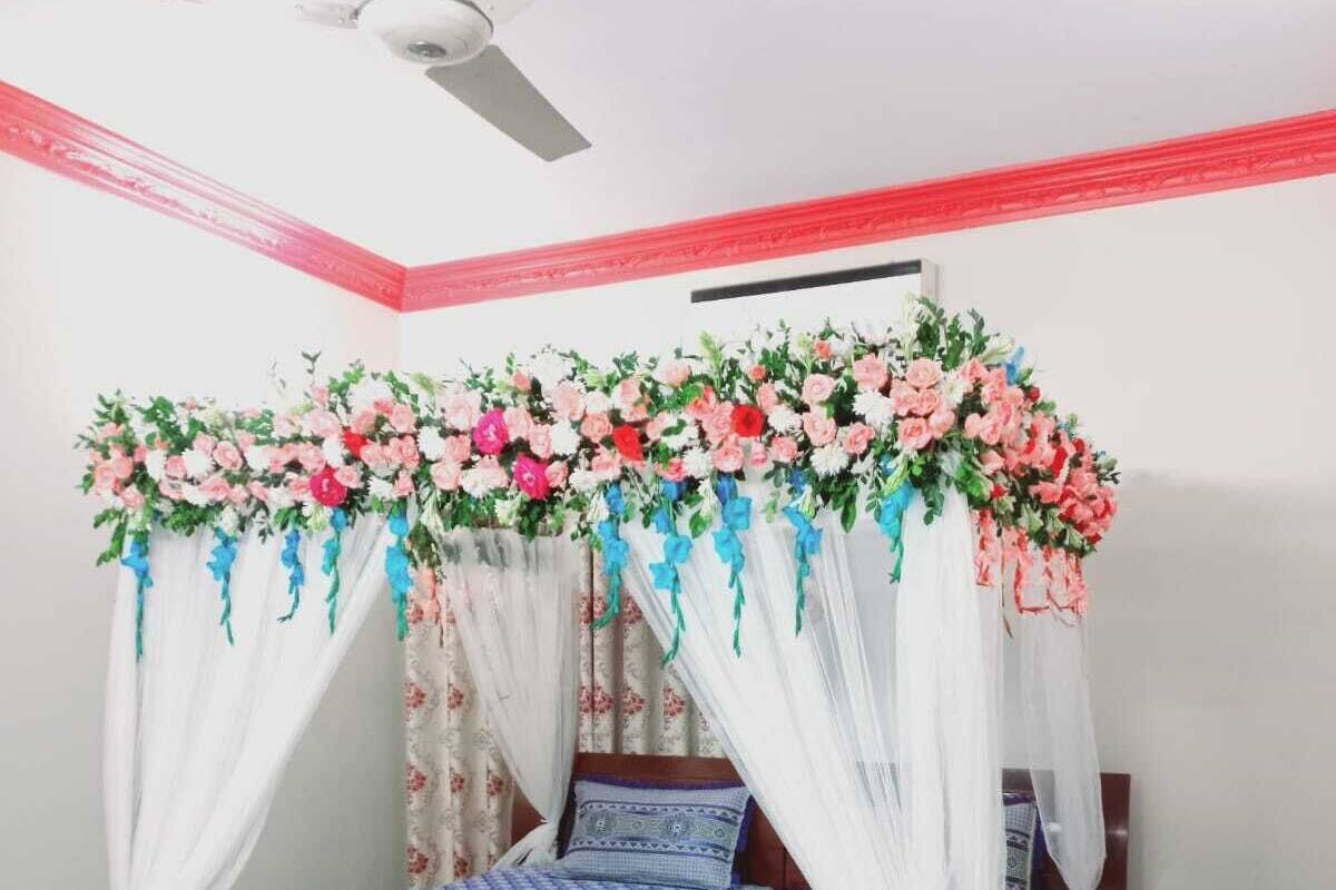 A bedroom with a bed, a ceiling fan, and a floral canopy.