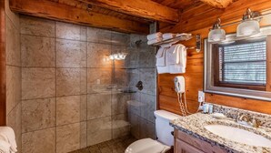 Et badeværelse med brusebad, toilet og vaskebord med vask og spejl.