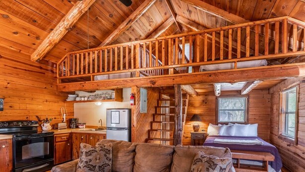 Una cabaña con habitación en el entrepiso, cocina y sala de estar.
