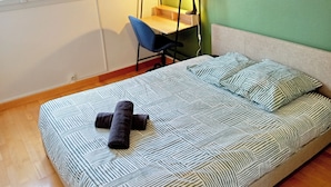 Un dormitorio con cama, escritorio, silla, ventana y pared verde.