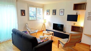 Una sala de estar con sofá, dos sillones, televisor y una mesita.