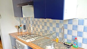 Cocina compacta con estufa a gas, lavadora y pileta.