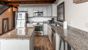 A modern kitchen with granite countertops, stainless steel appliances, and a wooden ceiling. - The Foxfire Cabin - Tree-top Getaway (Ponca)