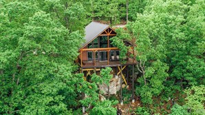 A wooden cabin with a balcony, surrounded by dense green forest. - The Foxfire Cabin - Tree-top Getaway (Ponca)