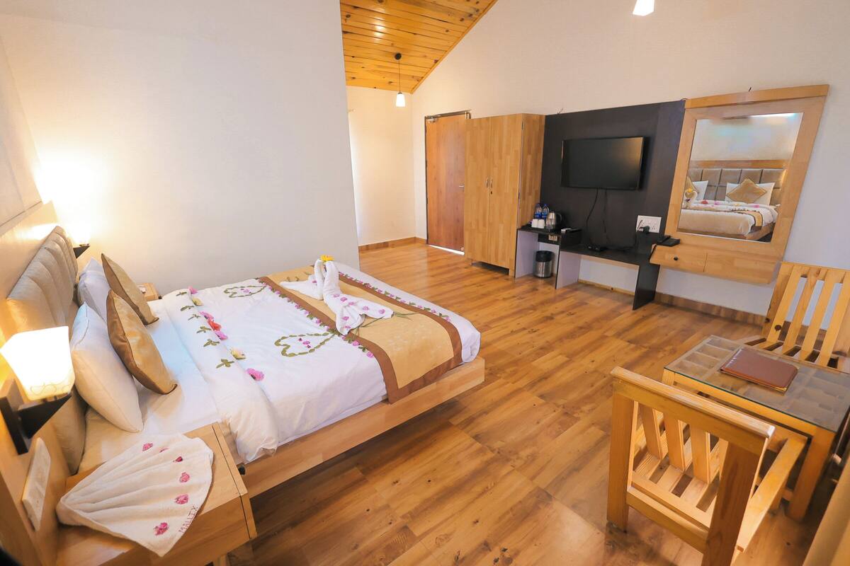 Un dormitorio con una cama de madera, un escritorio, una silla, un televisor y un armario.