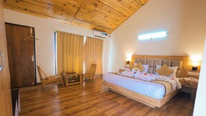 Un dormitorio con suelo de madera, una cama con cabecero, una mesita de noche y una silla.