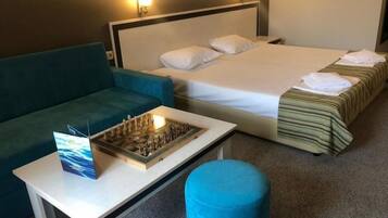 A hotel room with a bed, a sofa, a table, and a chessboard.