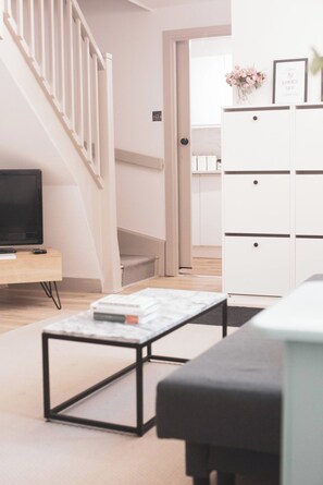 A modern living room with a TV, a coffee table, and a white cabinet. - Entire 2 Bedroom House 7m To Station (Barnet)