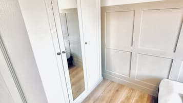A room with a wardrobe, a bed, and a wooden floor.