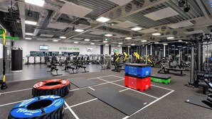 Un gimnasio con equipo de ejercicio variado, un saco de boxeo y un letrero motivacional en la pared.