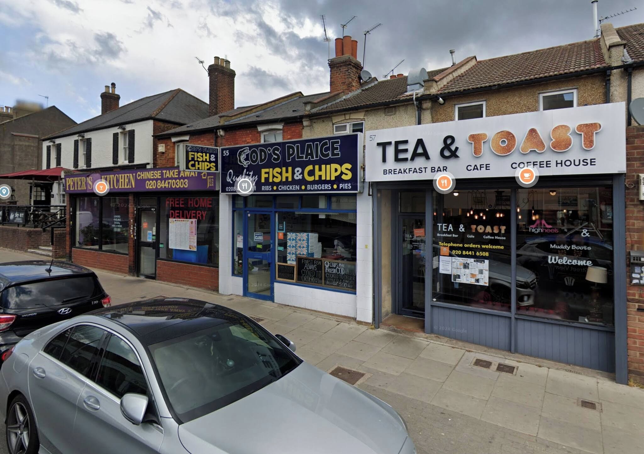 A street view with various shops including a fish and chips restaurant, a coffee house, and a breakfast bar.