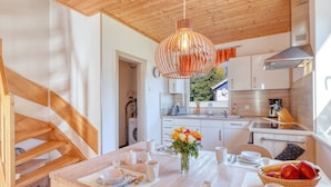 A modern kitchen with wooden accents, a dining area with a table set for two, and a view of the outside. - Beautiful apartment in villa for 4 people with WIFI, TV and terrace (Stralsund)