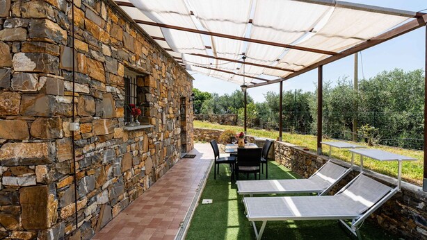 A stone building with a covered patio area, outdoor seating, and a view of the surrounding landscape. - Cosy apartment for 4 people with WIFI, pool, A/C and pets allowed (Civezza)
