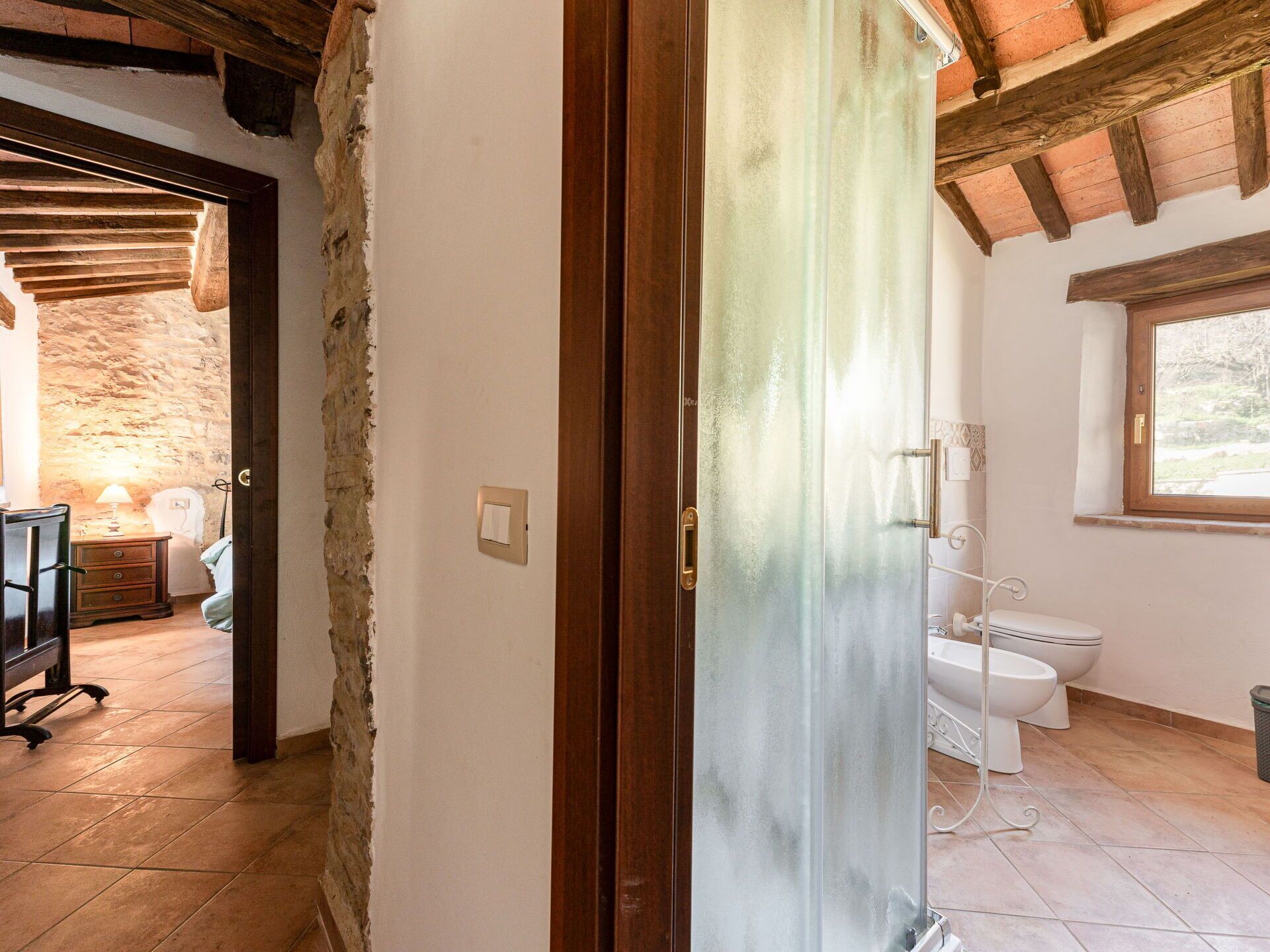 A bathroom with a toilet, a bidet, and a window.