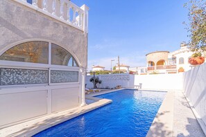 Ein Swimmingpool mit weißer Wand und einem Balkon.