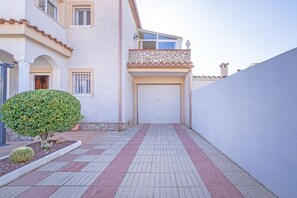 Ein Gebäude mit Garage, kleinem Garten und Pflasterweg.