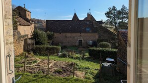 A stone building with a tiled roof, a small garden with raised beds, and a metal water tank. - Chez Max et Juliette - Traditional Stone house in historic Burgundy village (Burnand)