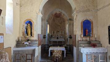 Un interior con un altar central, dos altares laterales y una estatua a la izquierda.