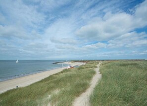 A coastal landscape with a sandy beach, grassy dunes, and a clear sky. - Bright Apartment Near Beach (Westkapelle)